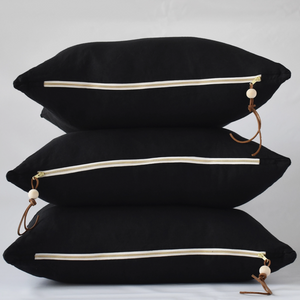 Black linen pillow with white and gold zipper.
